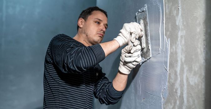 man applies insulation to a bathroom wall.