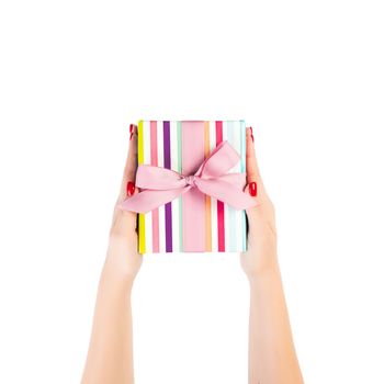 Woman hands give wrapped Christmas or other holiday handmade present in colored paper with pink ribbon. Isolated on white background, top view. thanksgiving Gift box concept.