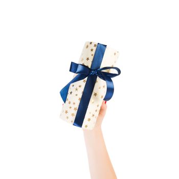 Woman hands give wrapped Christmas or other holiday handmade present in gold paper with blue ribbon. Isolated on white background, top view. thanksgiving Gift box concept.