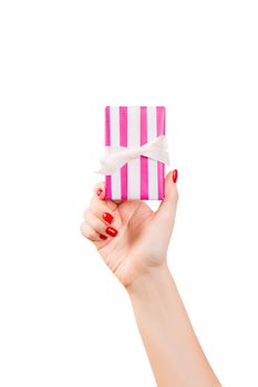 Woman hands give wrapped Christmas or other holiday handmade present in pink paper with white ribbon. Isolated on white background, top view. thanksgiving Gift box concept.