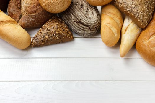 assortment of baked bread on wood table. top view with copy space.