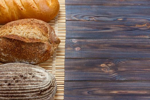 assortment of baked bread on wood table. top view with copy space.