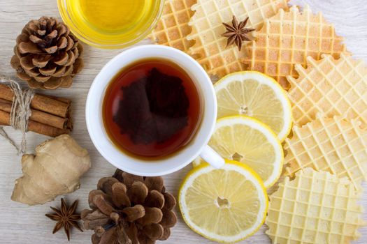 Cup of tea with Christmas decor, honey, pinecone, badian, ginger, waffles and cinnamon