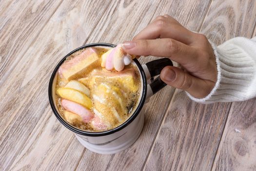 Close up hands of young woman female with manicure holding a cup of hot cocoa with marshmallow or coffee. Holiday Food Drink morning concept.