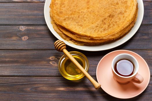 breakfast tea with pancakes and honey on wooden background.
