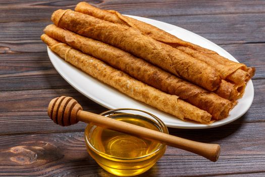 Stack of tasty pancakes with honey in jar on wooden bachground.