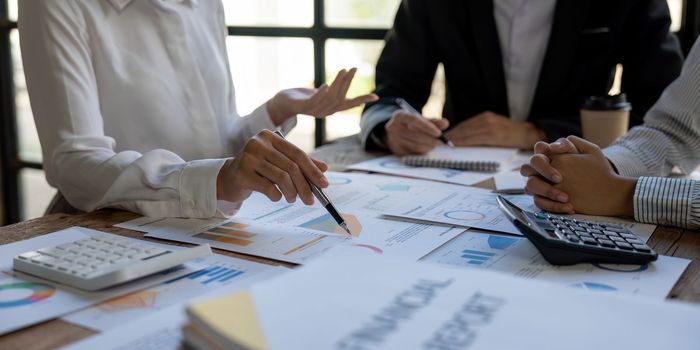 Business team finance or bookkeeper working with a calculator to calculate business data summary report, accountancy document and laptop computer at the office, business meeting concept.