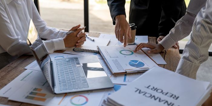 Business team finance or bookkeeper working with a calculator to calculate business data summary report, accountancy document and laptop computer at the office, business meeting concept.