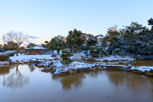 Snow covered landscape around small pond in castle park at sunrise. High quality photo