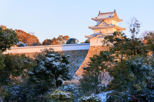 Early morning light hits historic Japanese castle with light dusting of snow . High quality photo