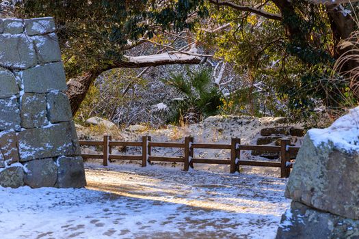 Golden morning light by ancient stone walls and snow covered walking path. High quality photo