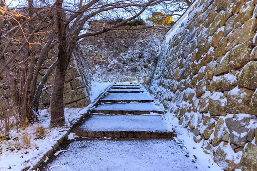 Snow covered stairs through ancient stone castle walls. High quality photo