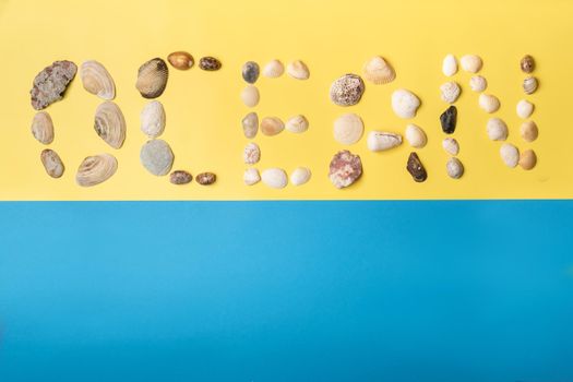 The inscription of the word ocean is made of shells on a yellow-blue background.Travel concept.
