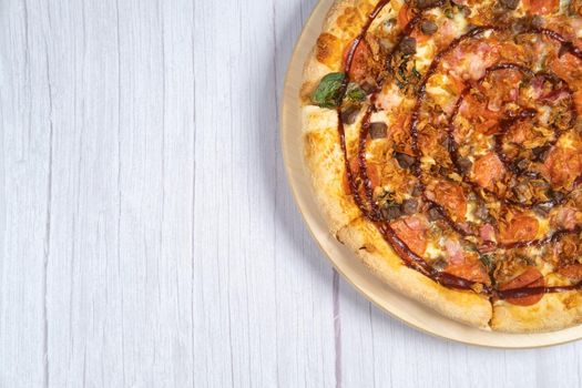 Delicious large pizza with bacon and spinach on a light wooden background.