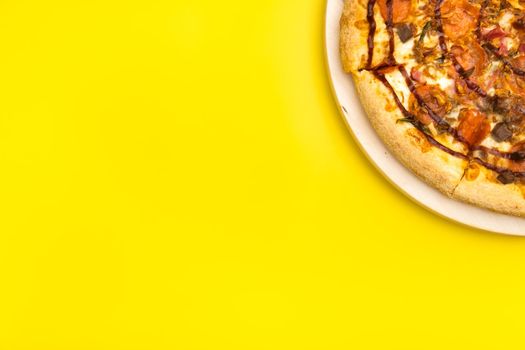 Delicious large pizza with bacon and spinach on a yellow background.