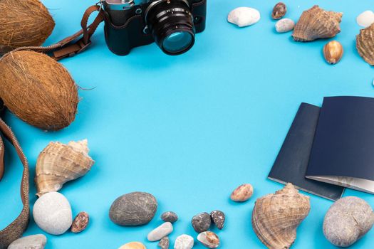 camera,coconuts, shells and documents on a blue background.Background for the traveler.