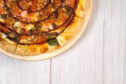 Delicious large pizza with bacon and spinach on a light wooden background.