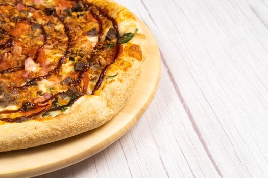 Delicious large pizza with bacon and spinach on a light wooden background.