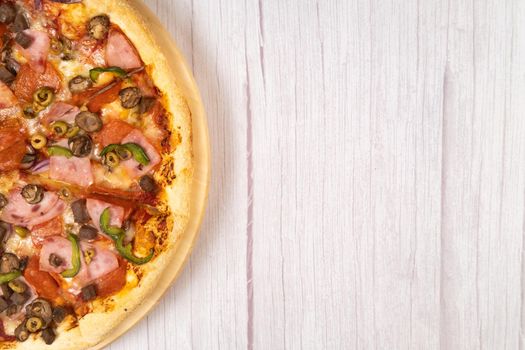 Delicious large pizza with veal and mushrooms on a light wooden background.