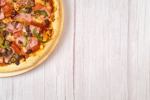 Delicious large pizza with veal and mushrooms on a light wooden background.