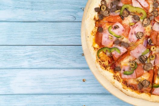 Delicious large pizza with veal and mushrooms on a blue wooden background.