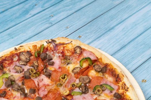 Delicious large pizza with veal and mushrooms on a blue wooden background.