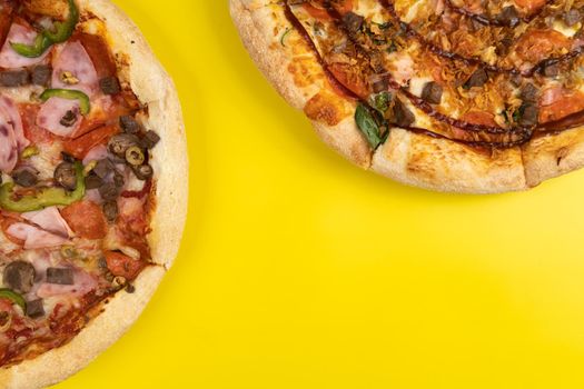 Two different Delicious big pizzas on a yellow background.