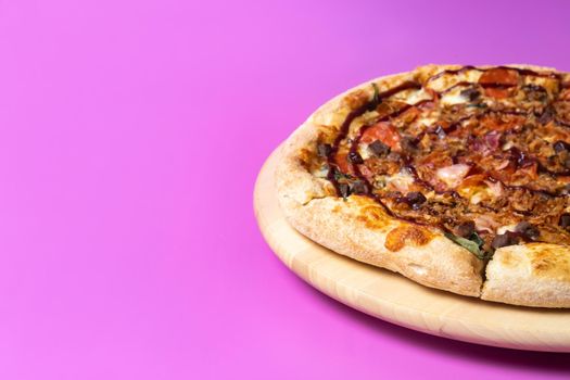 Delicious large pizza with bacon and spinach on a pink background.