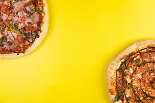 Two different Delicious big pizzas on a yellow background.