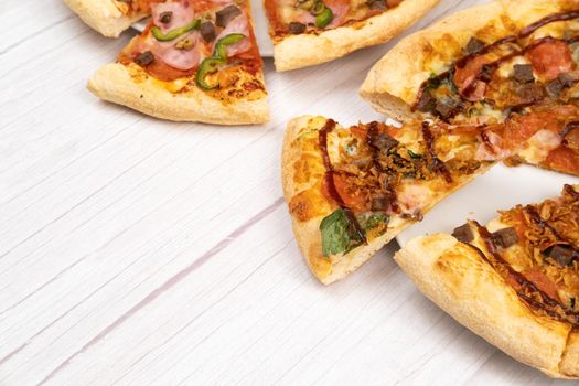 Two different delicious large pizzas on a light wooden background.
