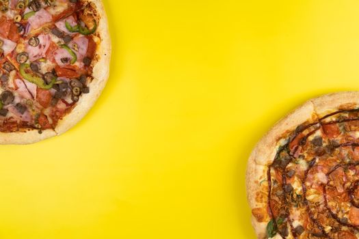 Two different Delicious big pizzas on a yellow background.