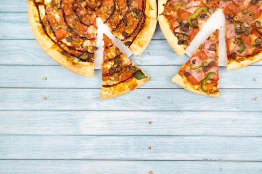 Two different delicious big pizzas on a blue wooden background.
