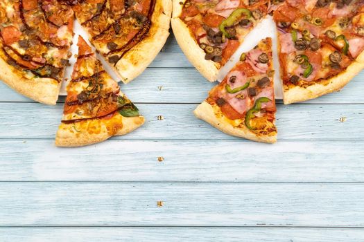 Two different delicious big pizzas on a blue wooden background.