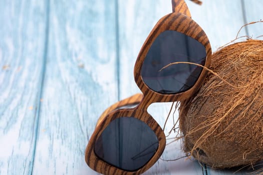 whole coconuts and wooden glasses on a blue wooden background.