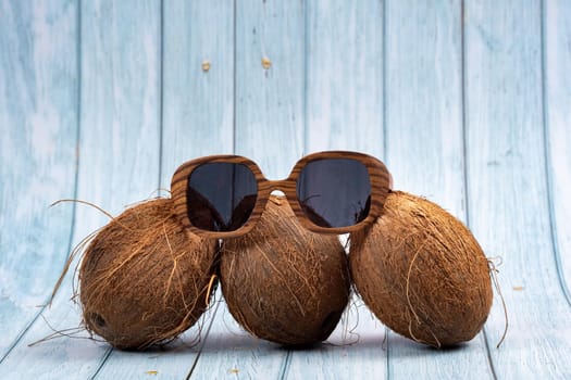 three whole coconuts and wooden glasses on a blue wooden background.