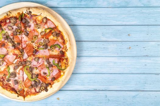 Delicious large pizza with veal and mushrooms on a blue wooden background.