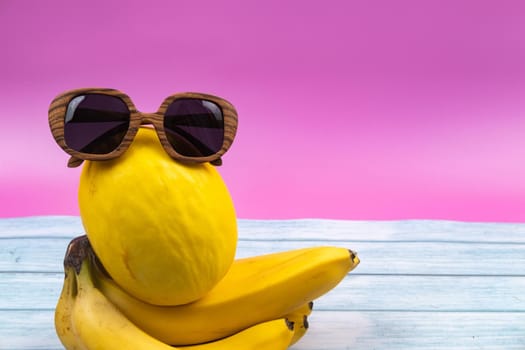 An assortment of yellow fruits and glasses lies on a pink background.