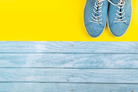 The blue shoes stand on an isolated mixed blue and yellow background.