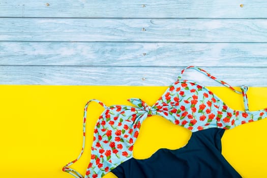 Top view of the swimsuit lying on a blue wooden and yellow background.Summer vacation concept.