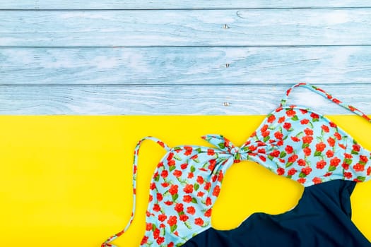 Top view of the swimsuit lying on a blue wooden and yellow background.Summer vacation concept.