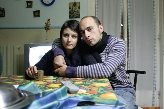 A couple of lovers embraced sitting on a table in a house room