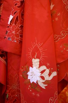 Close up of a typical red Christmas tablecloth with the embroidery of a candle