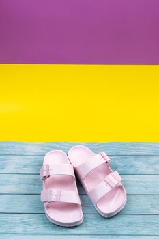 Pink sneakers stand on an isolated mixed color background.