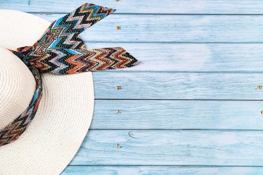 Top view of a straw white hat lying on a blue wooden background.The concept of summer holidays.