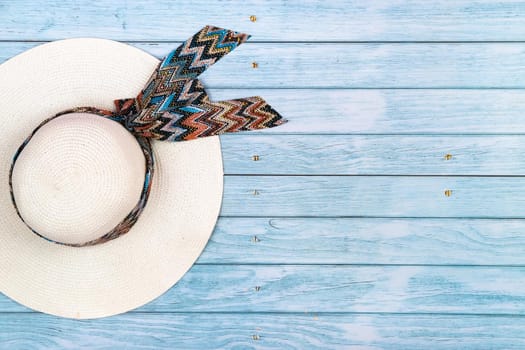 Top view of a straw white hat lying on a blue wooden background.The concept of summer holidays.