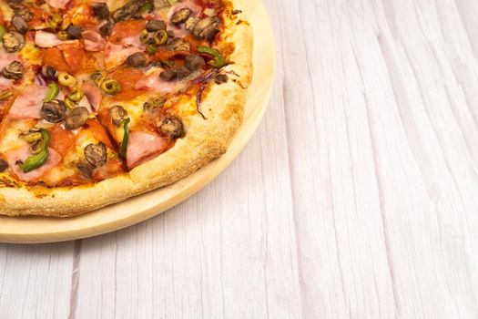 Delicious large pizza with veal and mushrooms on a light wooden background.