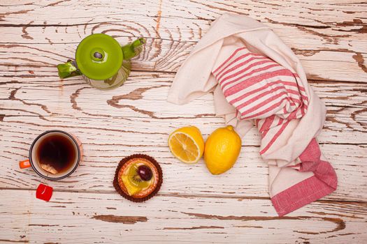 Flat lay of rural breakfast. Top view of vintage teacup and cup with lemon and pastry on white wooden table