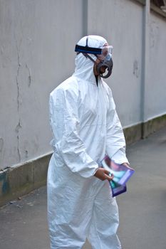 Young woman wearing protective white jumpsuit handing out information brochures in the empty street