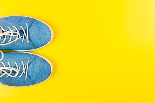 Blue shoes stand on an isolated yellow background.