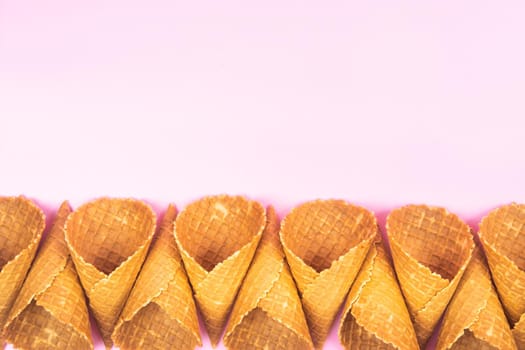 Empty waffle cones for ice cream on a pink background.